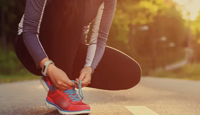 Mujer atándose los cordones de los zapatos antes de trotar