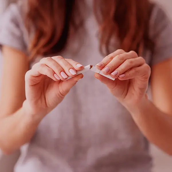 Mujer rompiendo en dos un cigarrillo